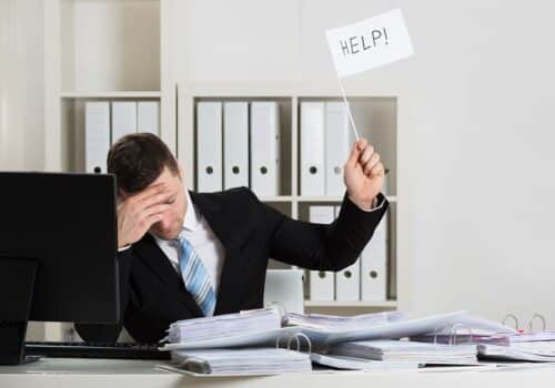 Overworked Accountant Holding Help Sign While Working